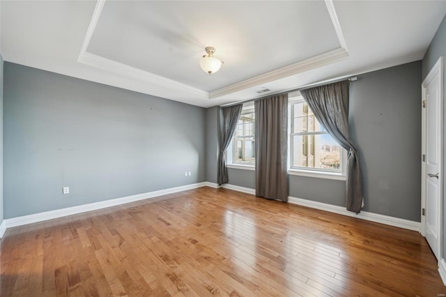 spare room featuring light hardwood / wood-style flooring and a raised ceiling