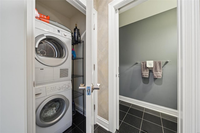 laundry area with dark tile patterned flooring and stacked washer / drying machine