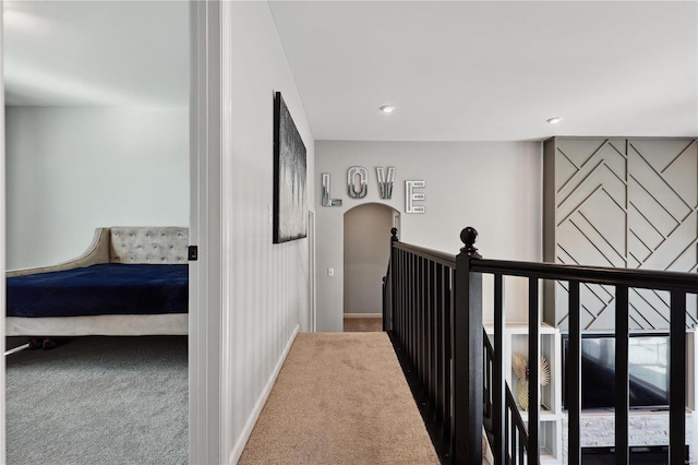 hallway featuring carpet, arched walkways, and baseboards