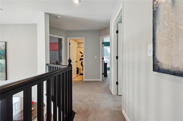 corridor with carpet floors, baseboards, and an upstairs landing