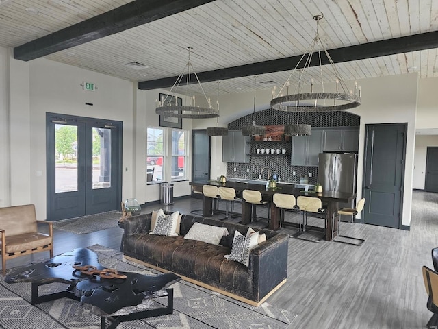 living room with a towering ceiling, french doors, wood finished floors, and beam ceiling