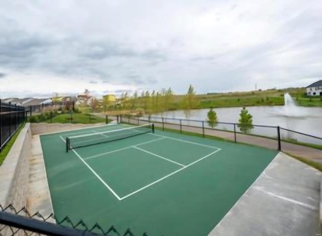 view of sport court with a water view and fence