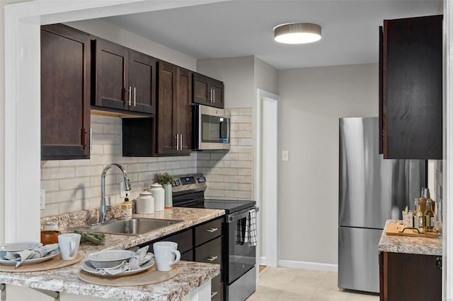 kitchen featuring sink, light stone countertops, tasteful backsplash, dark brown cabinets, and stainless steel appliances