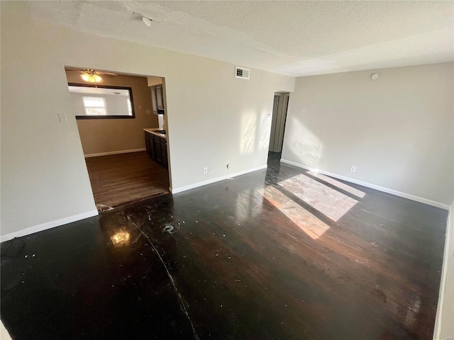 spare room featuring ceiling fan, dark wood-type flooring, and a textured ceiling