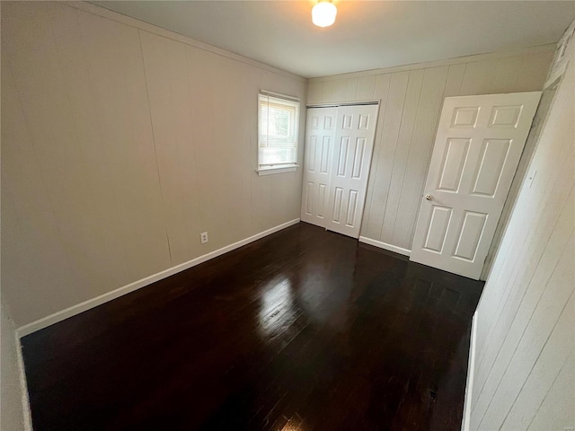 unfurnished bedroom featuring crown molding, a closet, and dark hardwood / wood-style floors