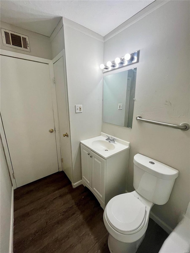 bathroom with vanity, toilet, wood-type flooring, and crown molding