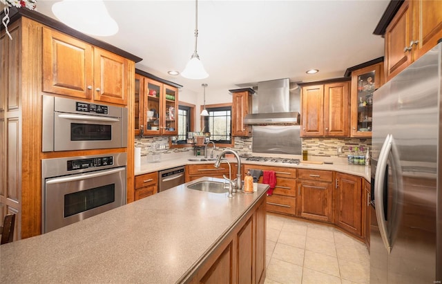 kitchen with decorative light fixtures, stainless steel appliances, sink, wall chimney range hood, and light tile patterned flooring