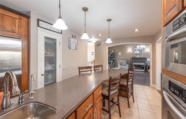 kitchen featuring appliances with stainless steel finishes, pendant lighting, a breakfast bar, a fireplace, and sink