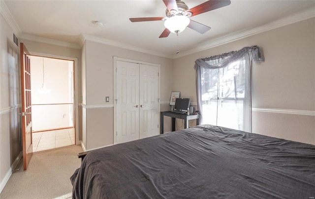 carpeted bedroom featuring ceiling fan, a closet, and crown molding