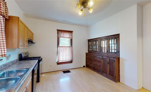 kitchen featuring gas range, sink, black dishwasher, extractor fan, and light wood-type flooring