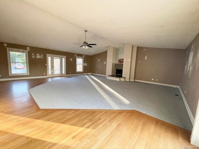 unfurnished living room with vaulted ceiling, ceiling fan, hardwood / wood-style floors, and plenty of natural light