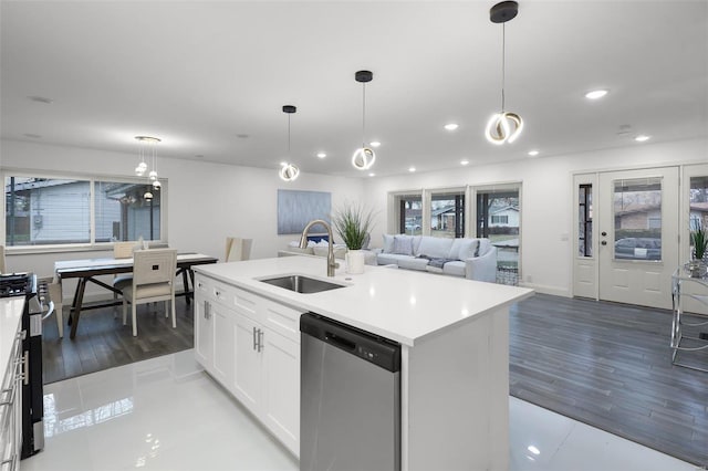 kitchen featuring appliances with stainless steel finishes, sink, a center island with sink, white cabinetry, and hanging light fixtures