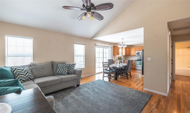 living room with ceiling fan with notable chandelier, light wood-type flooring, and lofted ceiling