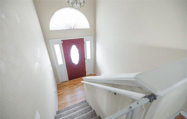 foyer entrance with hardwood / wood-style floors, a towering ceiling, and an inviting chandelier