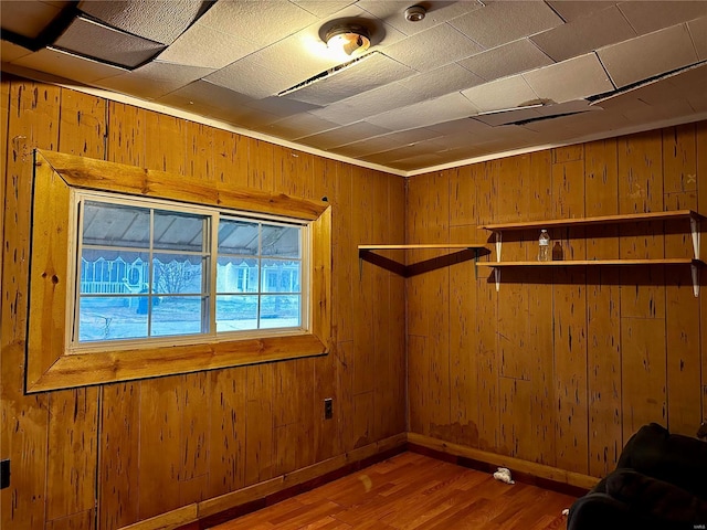 empty room featuring wood-type flooring, ornamental molding, and wooden walls