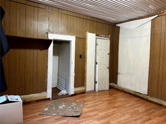 empty room featuring wood walls and light hardwood / wood-style floors