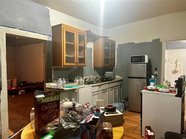 kitchen featuring stainless steel fridge, light hardwood / wood-style floors, and sink