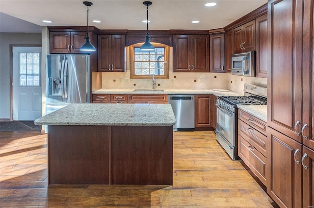 kitchen featuring light stone countertops, appliances with stainless steel finishes, a center island, and decorative light fixtures