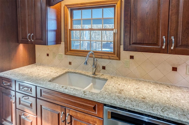 kitchen featuring sink, decorative backsplash, light stone countertops, and dishwasher