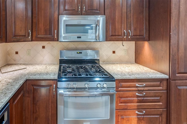 kitchen featuring light stone counters, stainless steel appliances, and backsplash