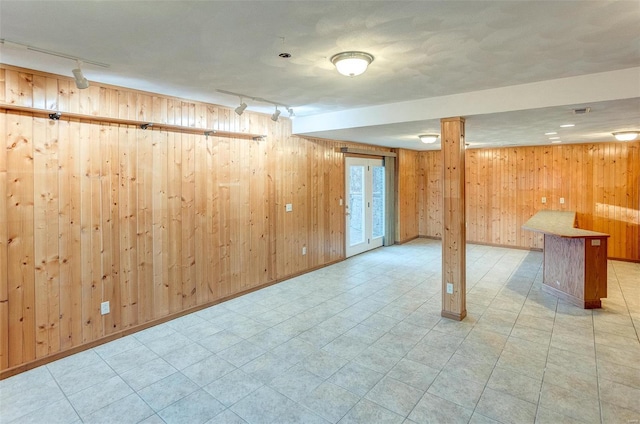 basement featuring rail lighting and wood walls