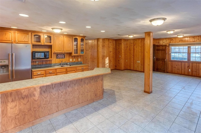 kitchen with sink, stainless steel fridge with ice dispenser, and wood walls