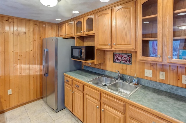 kitchen with sink, light tile patterned floors, wooden walls, and stainless steel fridge