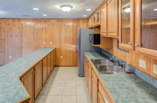 kitchen featuring light tile patterned flooring, sink, and wooden walls