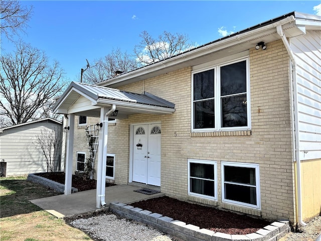 view of front of property with metal roof, a patio area, and brick siding