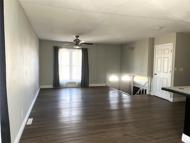 spare room featuring dark wood-style floors, ceiling fan, and baseboards