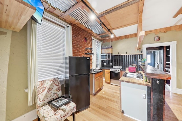 kitchen featuring wooden counters, light wood-type flooring, light brown cabinetry, stainless steel appliances, and brick wall