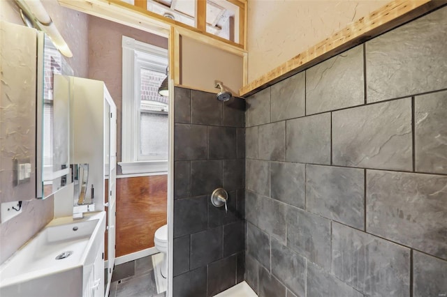 bathroom featuring tiled shower and toilet