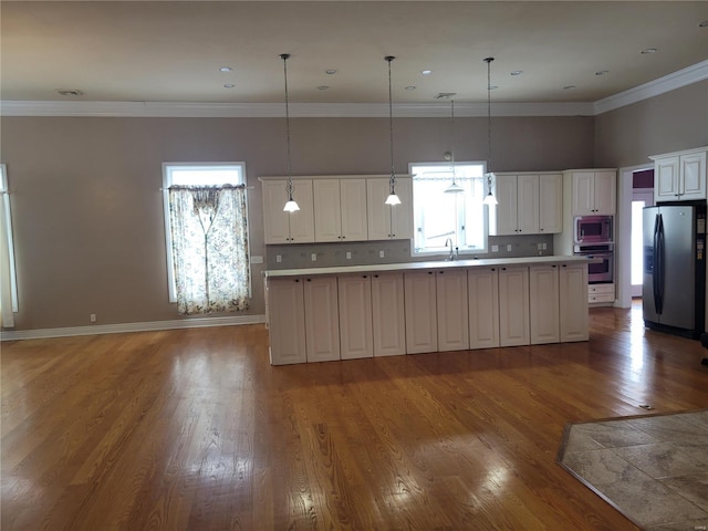 kitchen with pendant lighting, a center island, backsplash, and appliances with stainless steel finishes