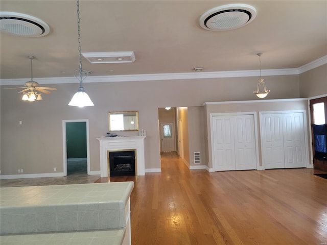 unfurnished living room featuring ceiling fan, wood-type flooring, and ornamental molding