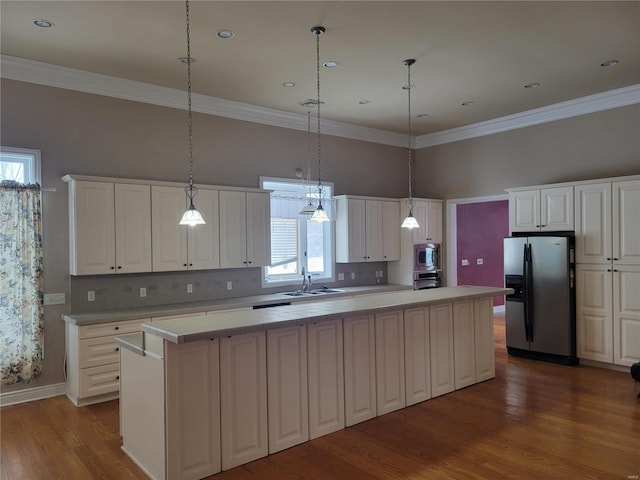 kitchen featuring white cabinetry, sink, a center island, decorative light fixtures, and appliances with stainless steel finishes