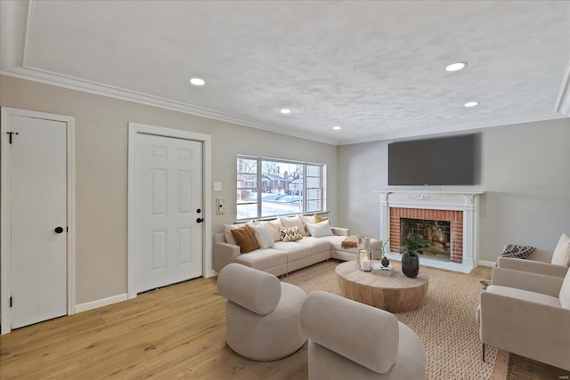 living room with a brick fireplace, ornamental molding, and light wood-type flooring