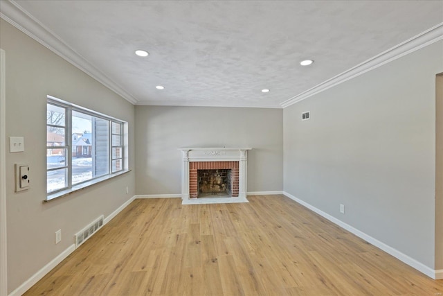 unfurnished living room with light wood-type flooring, a brick fireplace, and ornamental molding