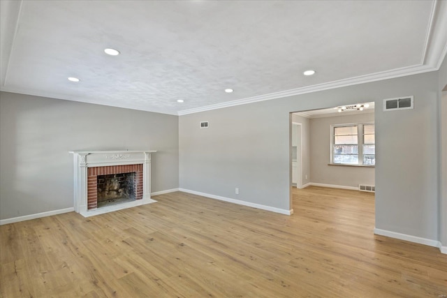 unfurnished living room featuring light wood-type flooring, a brick fireplace, and ornamental molding