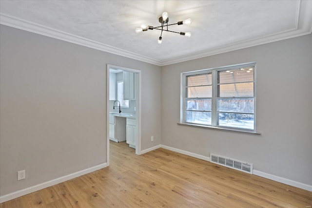 spare room with sink, ornamental molding, and a chandelier