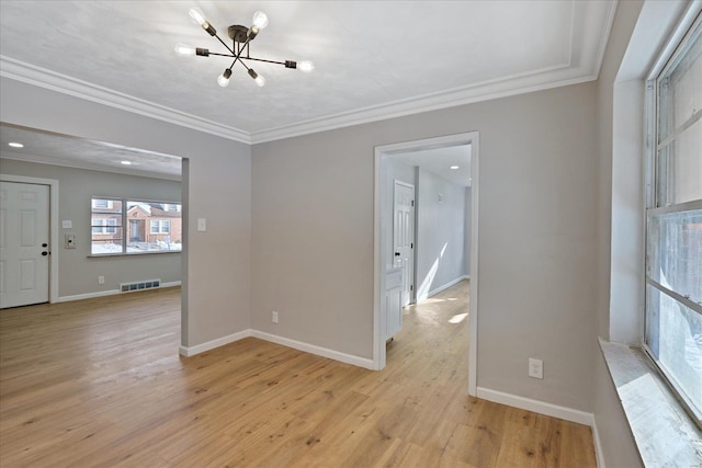 spare room featuring a chandelier, crown molding, and light hardwood / wood-style flooring