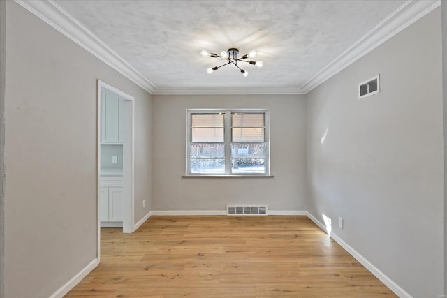 empty room with a textured ceiling, a notable chandelier, ornamental molding, and light hardwood / wood-style flooring