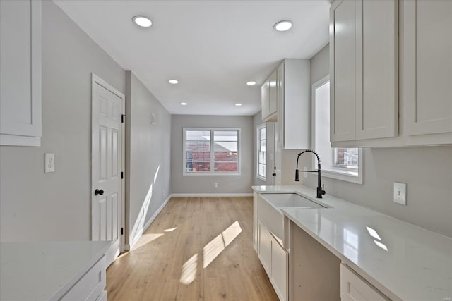 kitchen featuring white cabinets, light stone counters, and sink