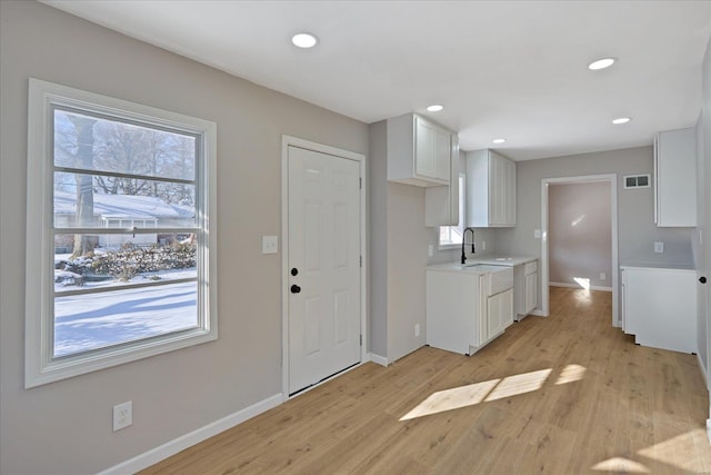 kitchen with white cabinets, light wood-type flooring, and sink