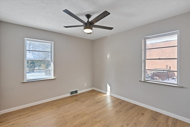 spare room with ceiling fan, plenty of natural light, and light wood-type flooring