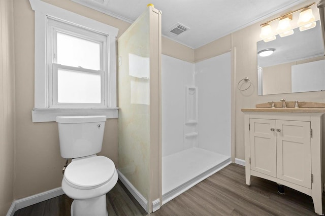 bathroom with vanity, crown molding, a shower, hardwood / wood-style floors, and toilet