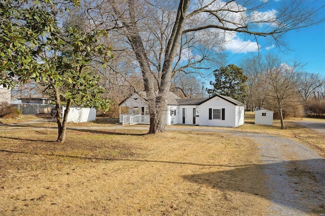 view of front of property featuring a storage shed and a front lawn