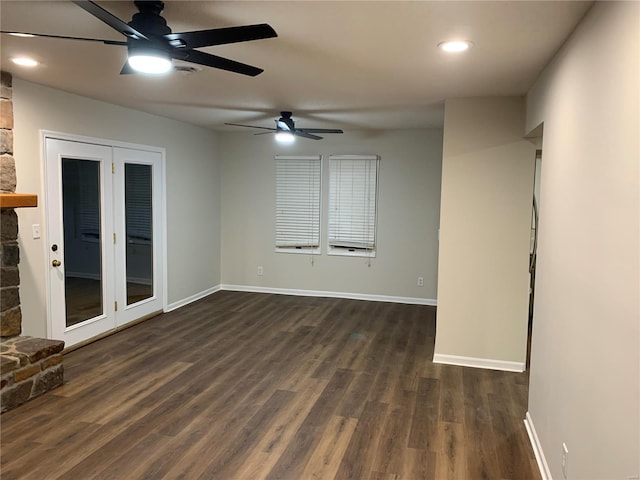 unfurnished room featuring a stone fireplace, ceiling fan, and dark hardwood / wood-style flooring