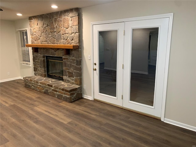 unfurnished living room featuring a stone fireplace and dark wood-type flooring