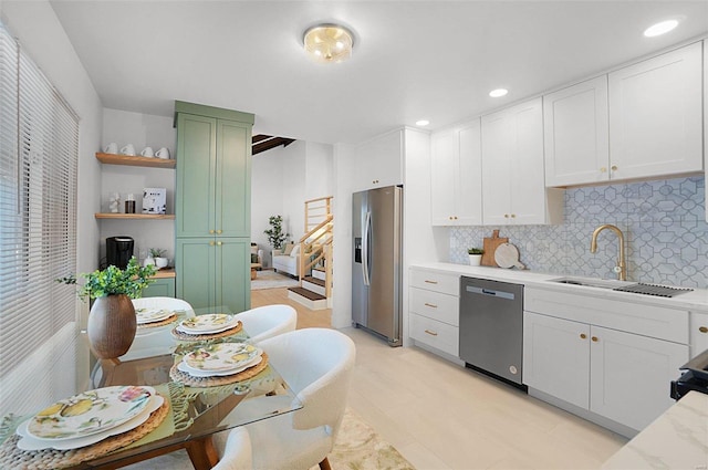 kitchen with sink, green cabinets, white cabinetry, decorative backsplash, and appliances with stainless steel finishes