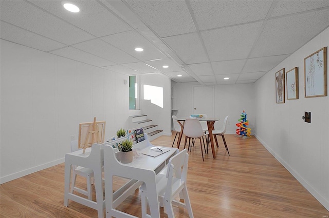 dining room with a drop ceiling and light wood-type flooring